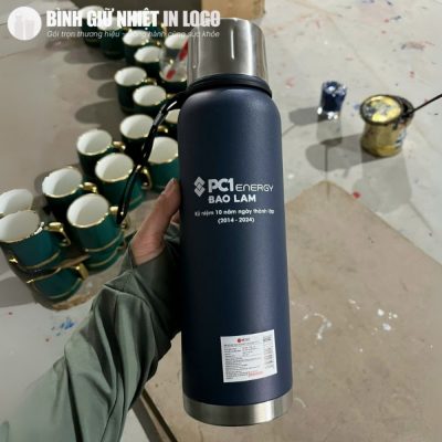 Cận cảnh thực tế bình giữ nhiệt Elmich xanh navy in logo sắc nét trên tay người dùng tại xưởng in