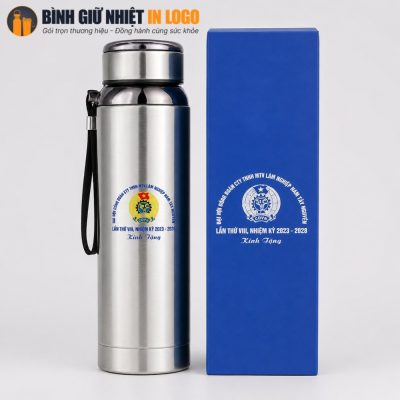 Cận cảnh chiếc bình giữ nhiệt GN-BN19 đặt cạnh hộp xi màu xanh dương in logo nhũ bạc