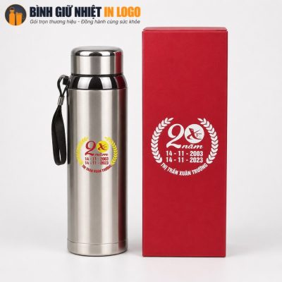 Bình giữ nhiệt inox 800ml đặt cạnh hộp xi đỏ lót lụa in logo kỷ niệm 20 năm thành lập Thị trấn Xuân Trường đồng bộ