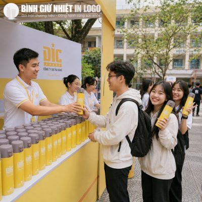 Các bạn trẻ hào hứng đón nhận bình giữ nhiệt Elmich màu vàng tại quầy sự kiện ngoài trời của doanh nghiệp