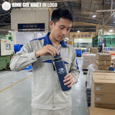 Nam công nhân dễ dàng mở nắp vặn của bình giữ nhiệt xanh navy ngay tại khu xưởng sản xuất