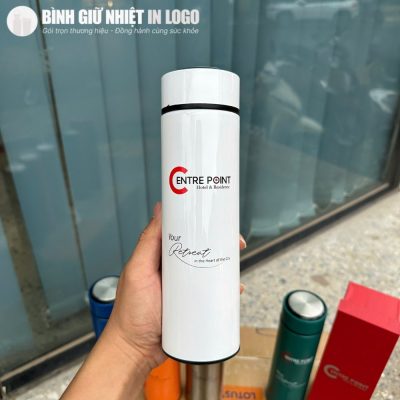 Cận cảnh bình giữ nhiệt màu trắng in logo Centre Point Hotel and Residence sắc nét trên tay người dùng