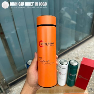 Cận cảnh bình giữ nhiệt màu cam nổi bật in logo thương hiệu Centre Point trên tay người dùng