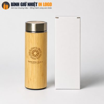 Bình giữ nhiệt vỏ tre đặt cạnh hộp giấy carton trắng