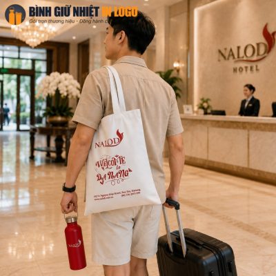 Khách lưu trú sử dụng túi canvas Nalod và bình giữ nhiệt đỏ khi di chuyển tại sảnh khách sạn