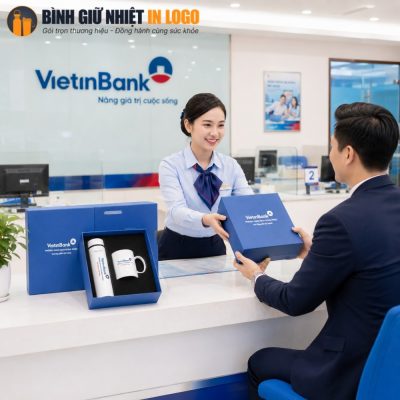 Nữ nhân viên VietinBank tươi cười trao tặng hộp quà màu xanh dương thanh lịch cho khách hàng nam tại quầy