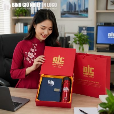 Nữ nhân viên mặc áo dài đỏ truyền thống cầm trên tay bộ quà tặng GN-GS09 tại bàn làm việc văn phòng.