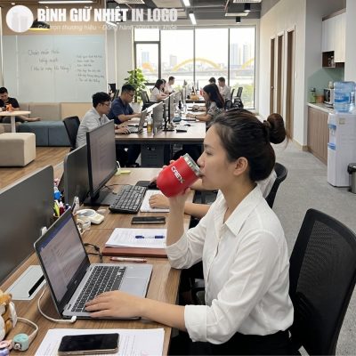 Nữ nhân viên văn phòng sử dụng cốc giữ nhiệt dáng trứng màu đỏ tại bàn làm việc