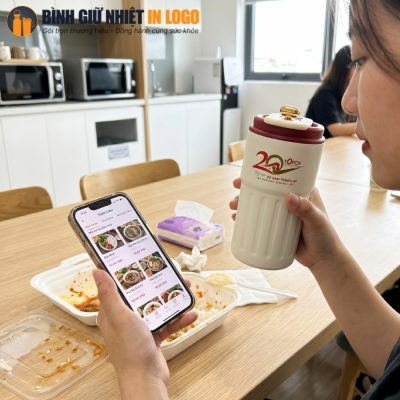 Nữ nhân viên văn phòng sử dụng cốc giữ nhiệt trong giờ nghỉ