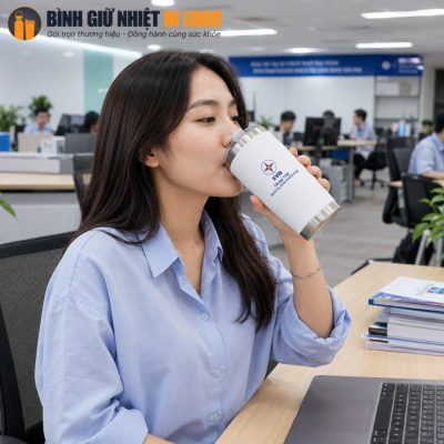 Nữ nhân viên văn phòng sử dụng ly giữ nhiệt GN-LC04 màu trắng in logo EVN tại bàn làm việc