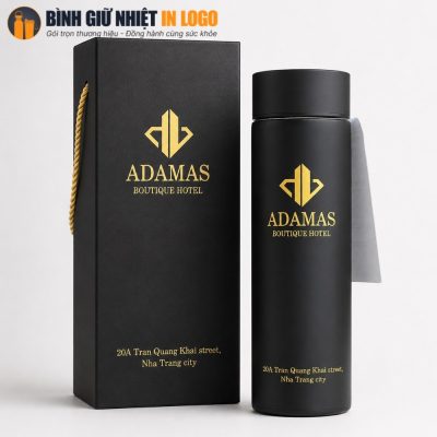 Cận cảnh bình giữ nhiệt đen nhám đặt cạnh hộp diêm quai xách in logo vàng kim