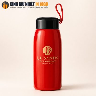 Cận cảnh bình giữ nhiệt màu đỏ bóng loáng in logo Le Sands nhũ vàng sắc nét